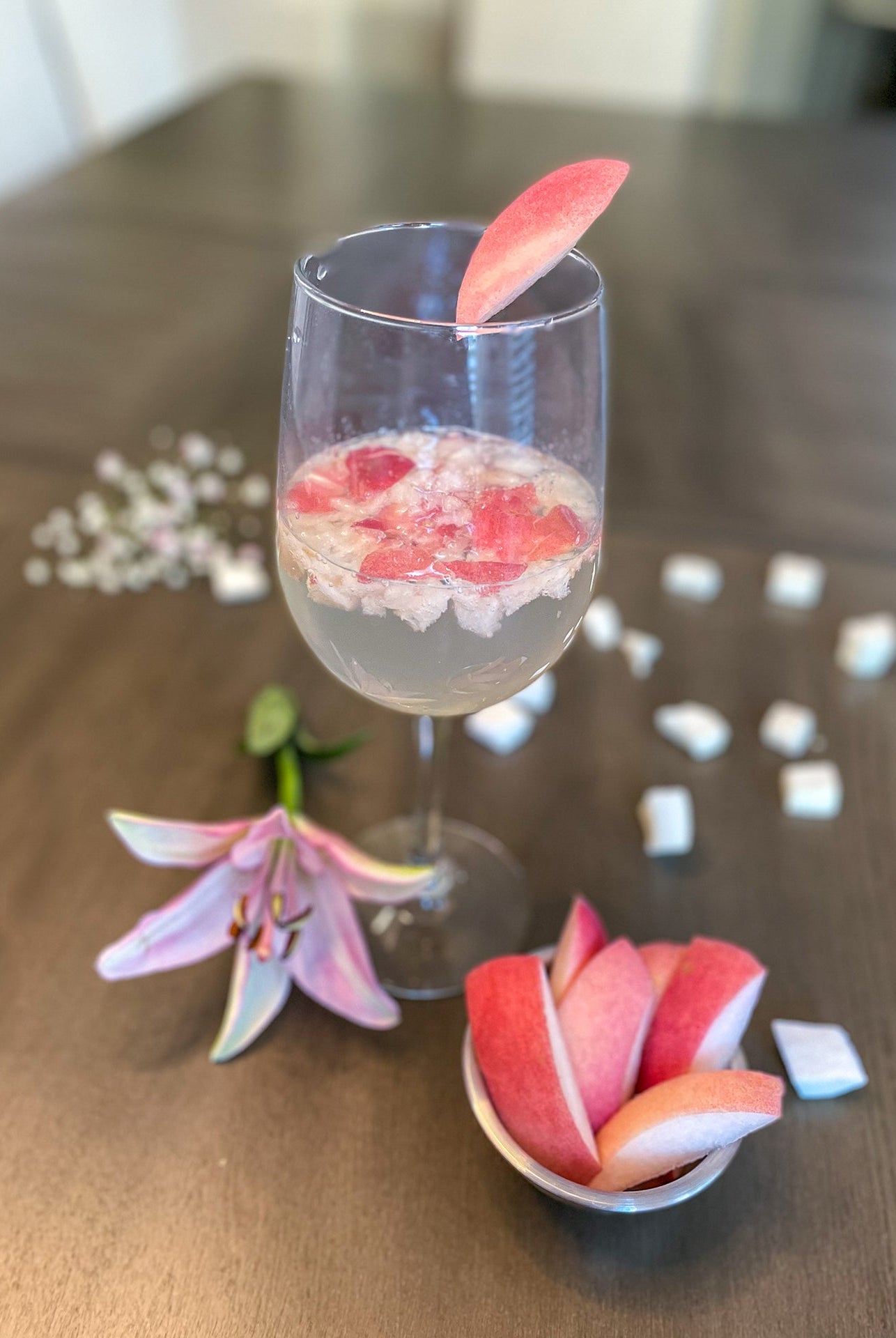 Flavored homemade seltzer with white peach and lily garnish.
