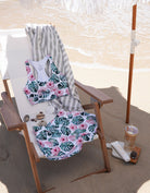 Pink Monstera runners and Kailani sports bra set on a beach chair on the beach with an umbrella and ocean in the background