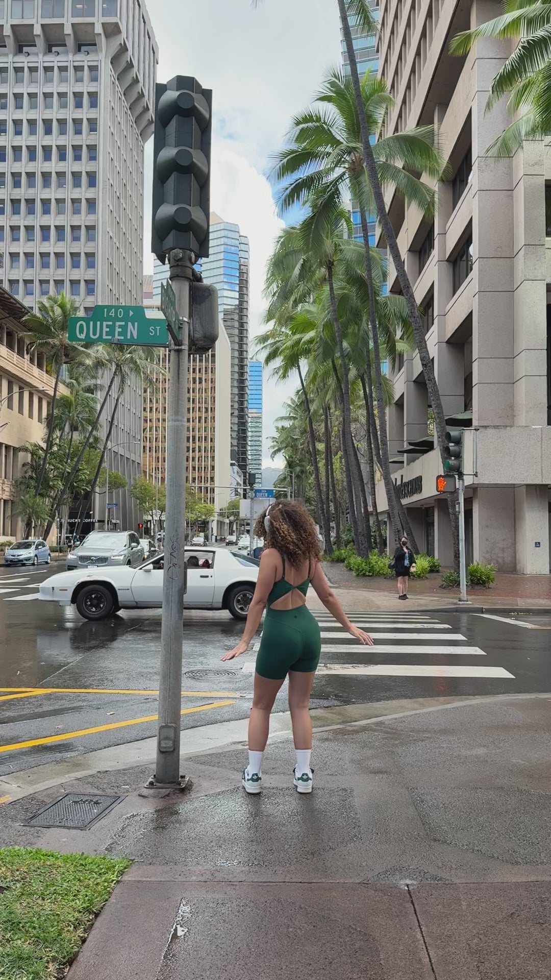 Love Fitness Dreamy Jumpsuit in the color evergreen. Model dancing on the side walk in downtown honolulu.