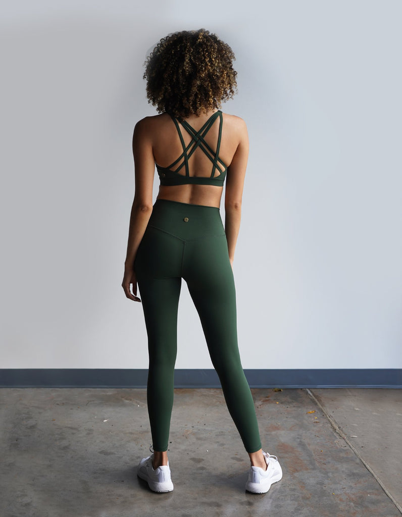 Love Fitness model showing the back detailing of the Leilani Sports bra and Essential Leggings in the beautiful color Eden
