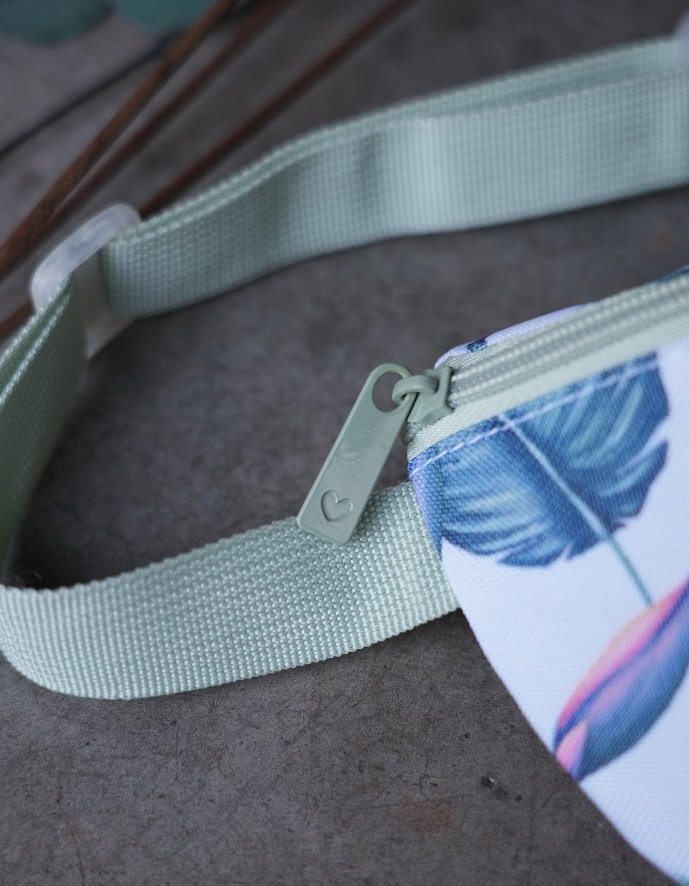 Love Fitness Tropical Paradise Fanny Packet up close picture showing the details of the zipper pull that is modern and engraved with the Love Fitness signature heart