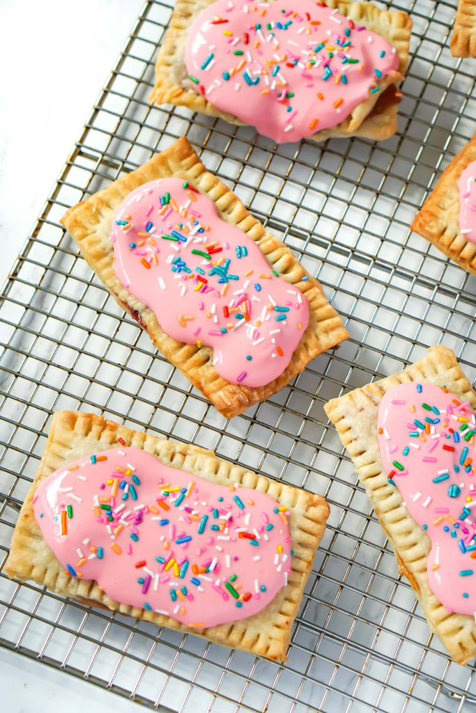 Homemade pop tarts recipe from Love Fitness Apparel x Alyssa Marie. Photo features pop tarts displayed don baking tray with pink frosting and colorful sprinkles. The pop tarts are gluten free and sugar free but look so yummy!