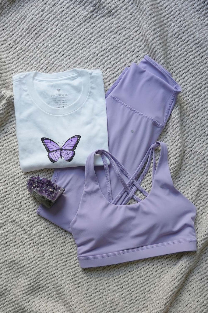 Flatlay image of Leilani Sports Bra - Blossom, Essential Leggings - Blossom, Lavender Butterfly White Cropped Tee, and Amethyst stone.