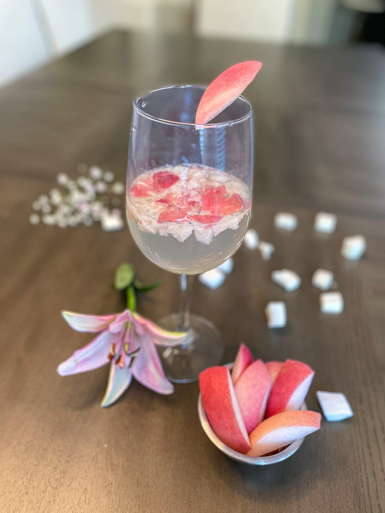 Flavored homemade seltzer with white peach and lily garnish.
