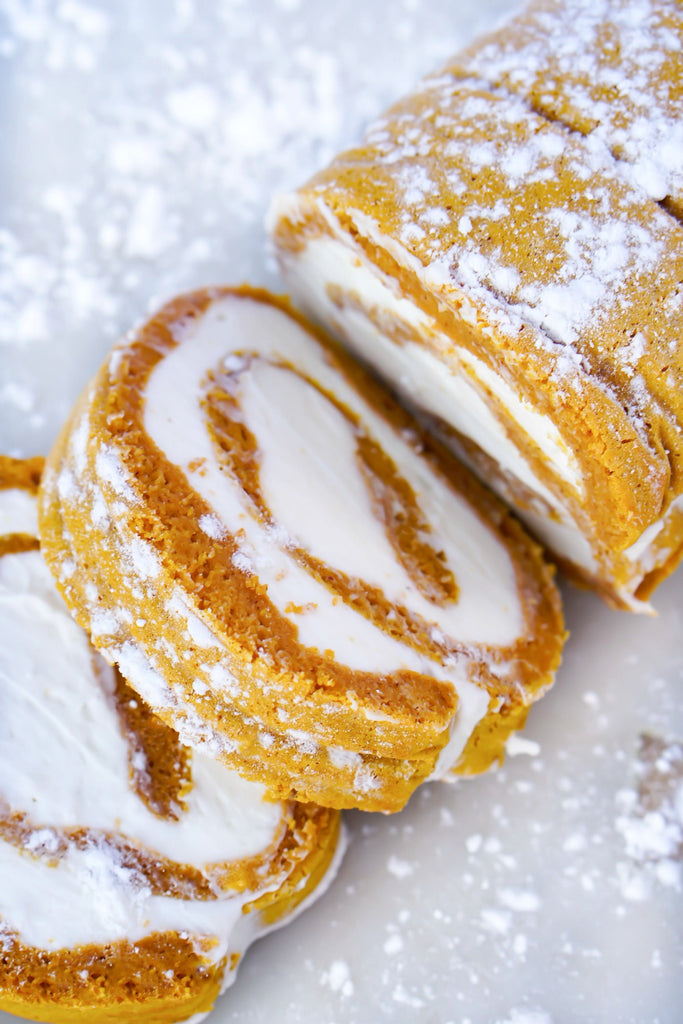 Image features cut slices of pumpkin twinkie rolls from the recipe with powdered sugar on top.