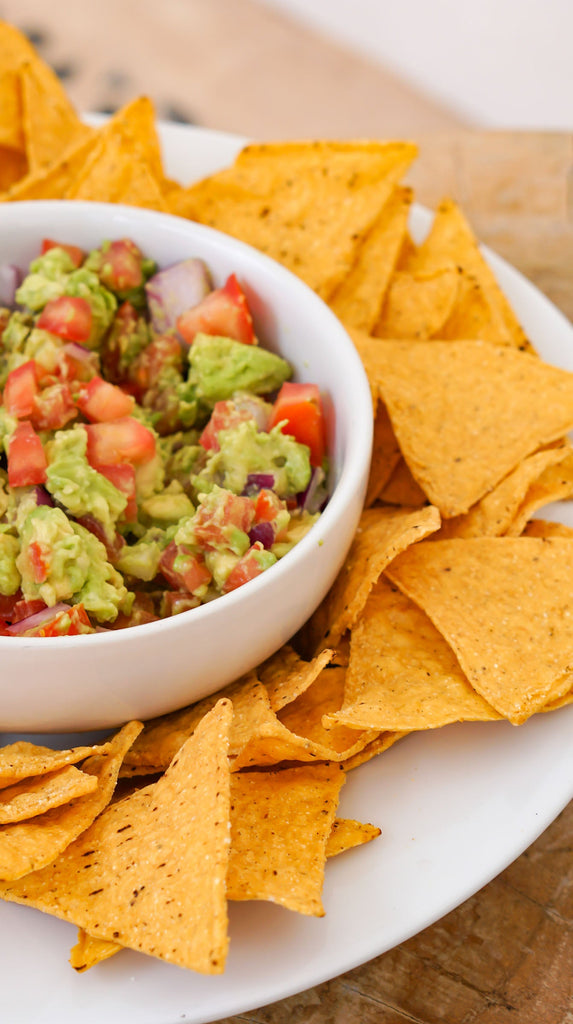 Guacamole recipe from Love Fitness Apparel x Alyssa Marie. Photo features chips surrounding bowl of homemade guacamole.