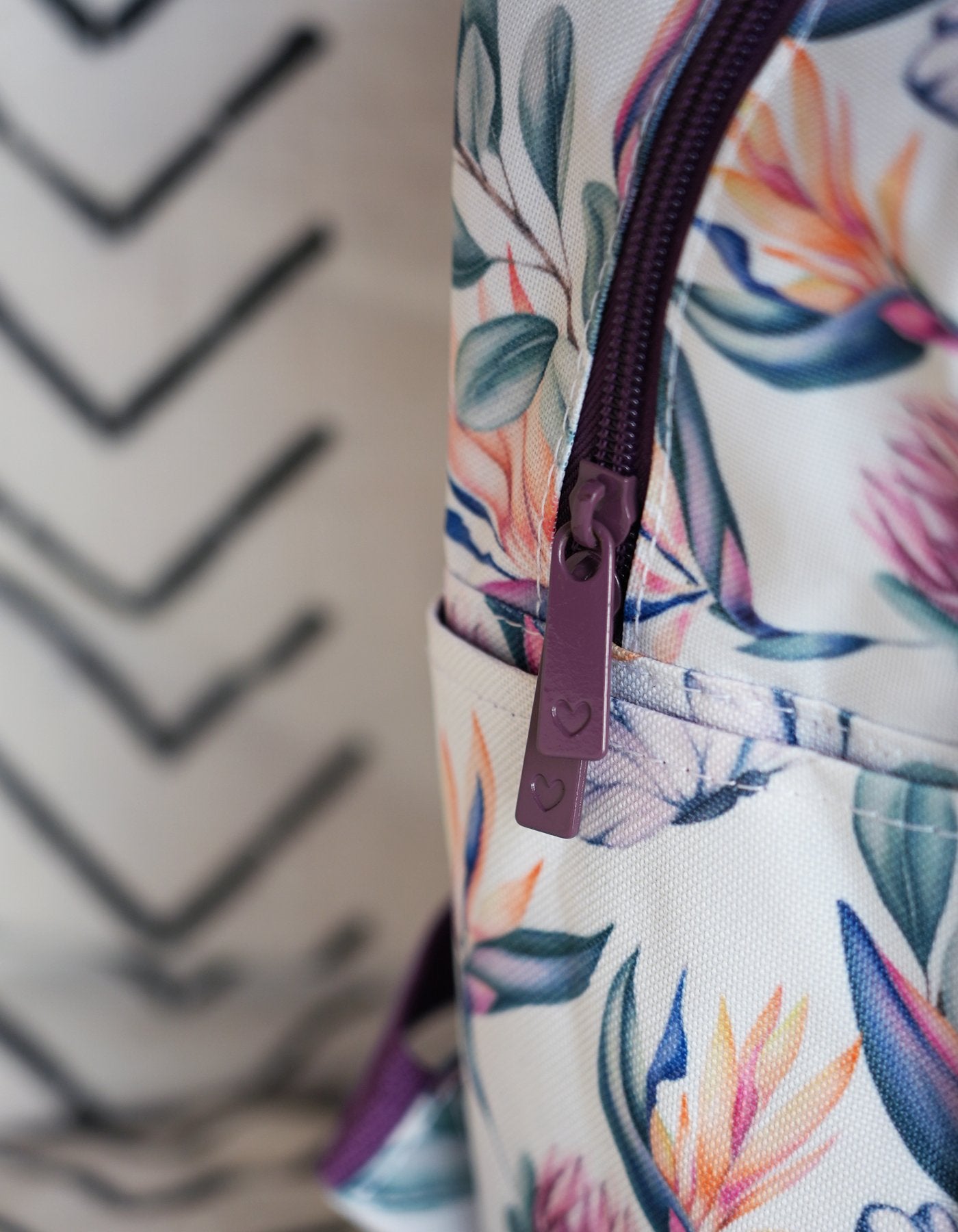 Side detailing of the mini back pack in the Island dreams print showing the zipper pulls with heart embossed detailing
