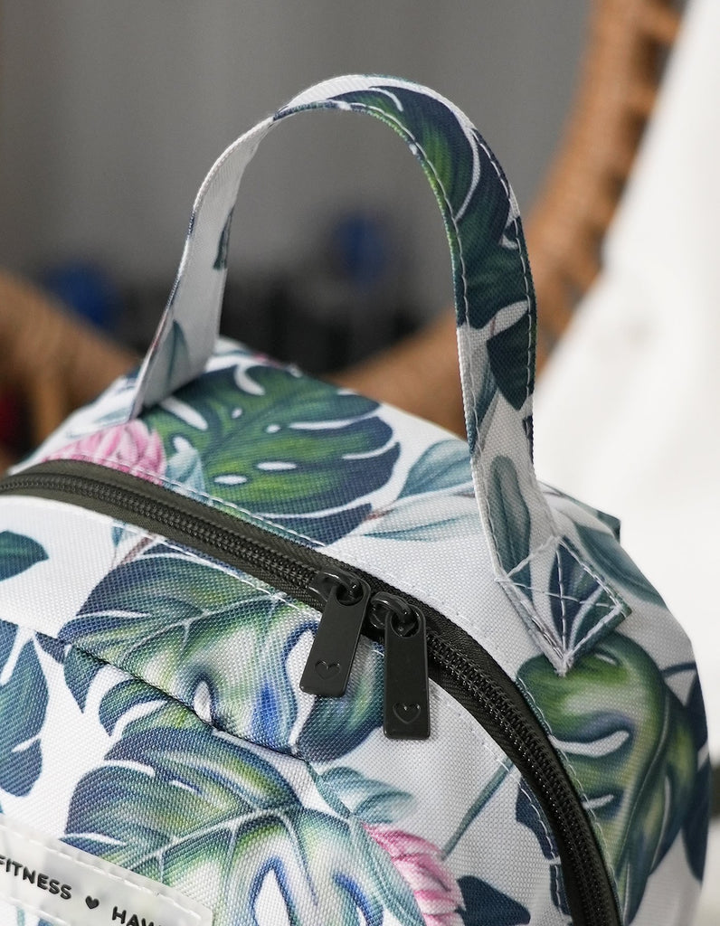 Up close picture of the Love Fitness Monsteral Mini Back Pack with all over Monstera Print and the dark olive green zipper and zipper pulls with heart logos. Oversized hand for easy carry