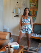 Model standing in a beautiful room wearing a dark green print with monstera leaves and tropical flowers