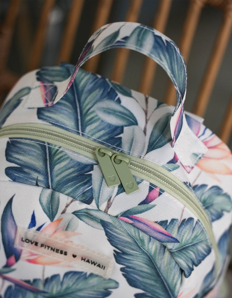 Close up to the beautiful neutral green zippers on top of the opening to the main compartment of the mini back pack in Tropical Paradise print and a oversized handle for easy carry 